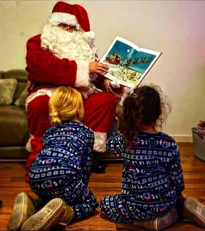Santa reading a Christmas story to two children in their pyjamas