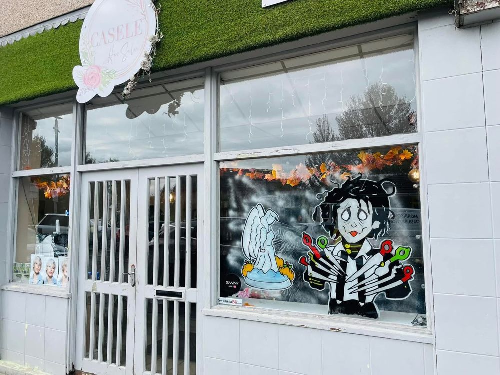 A hair salon shop front in Swansea with a painted Halloween window